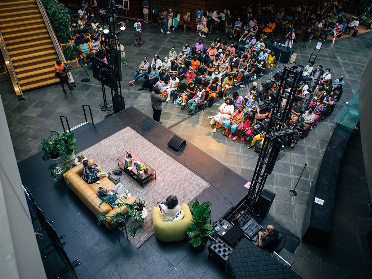 Un large public fait face à une scène équipée d'un canapé et d'une chaise pour les intervenants, dans une salle moderne où se tient une table ronde pendant le BlackStar Film Festival.