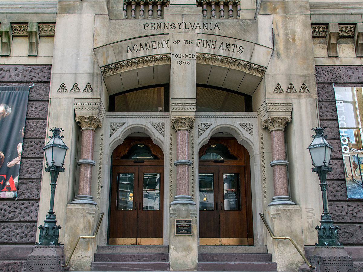 The arched double-door entrance to the Pennsylvania Academy of the Fine Arts, framed by intricate stonework and tall columns.
