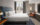 A hotel guestroom with a king bed with white linens, a orange accent chair and a window overlooking Philadelphia's City Hall.