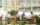 Two groups of people dine outdoors at Cafe Click in Philadelphia, enjoying meals at round tables surrounded by greenery and modern glass architecture.