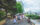 Visitantes passeiam pelo caminho à beira-mar no Spruce Street Harbor Park em um dia ensolarado. As árvores margeiam o caminho e o Benjamin Franklin Bridge é visto à distância.