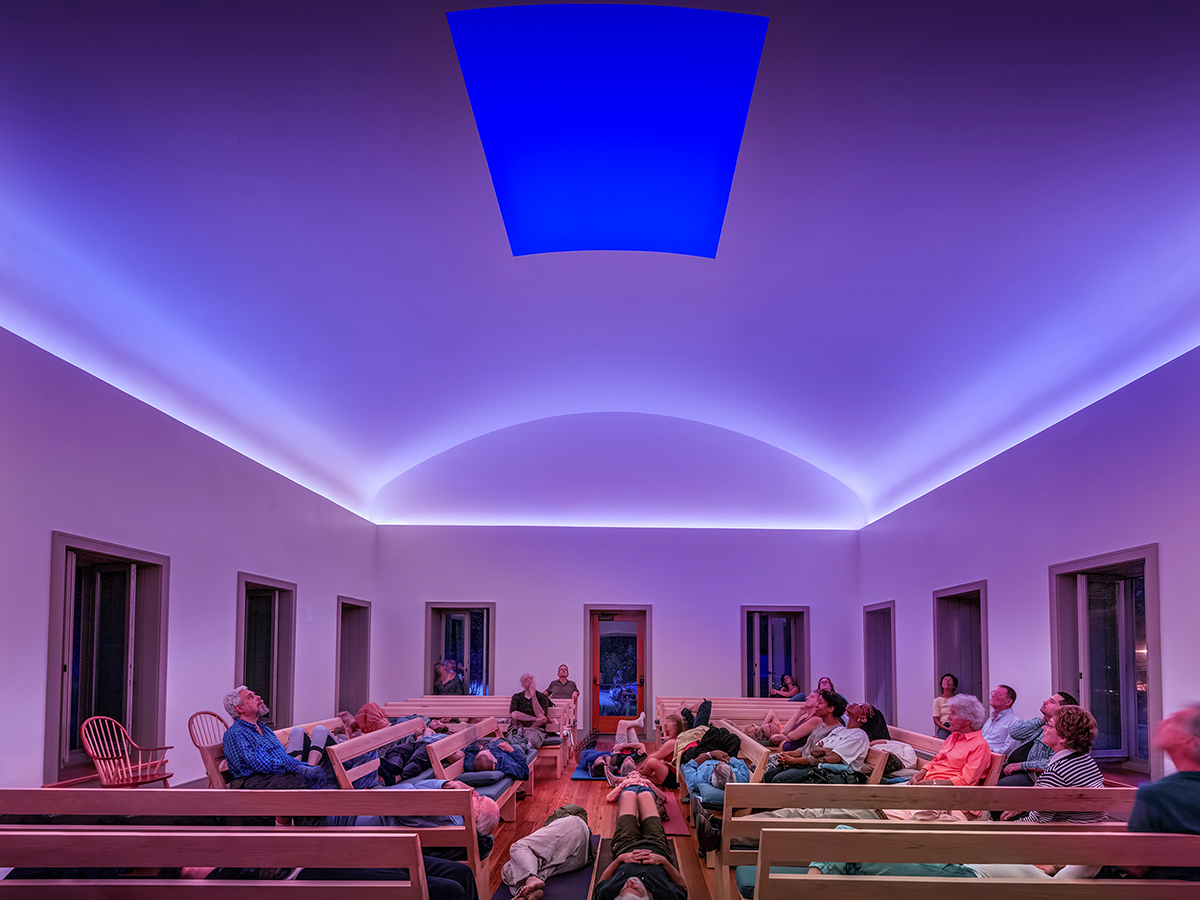Visitors at Chestnut Hill Skyspace watch the sunset during a hole in the roof while light is projected on the ceiling around it.