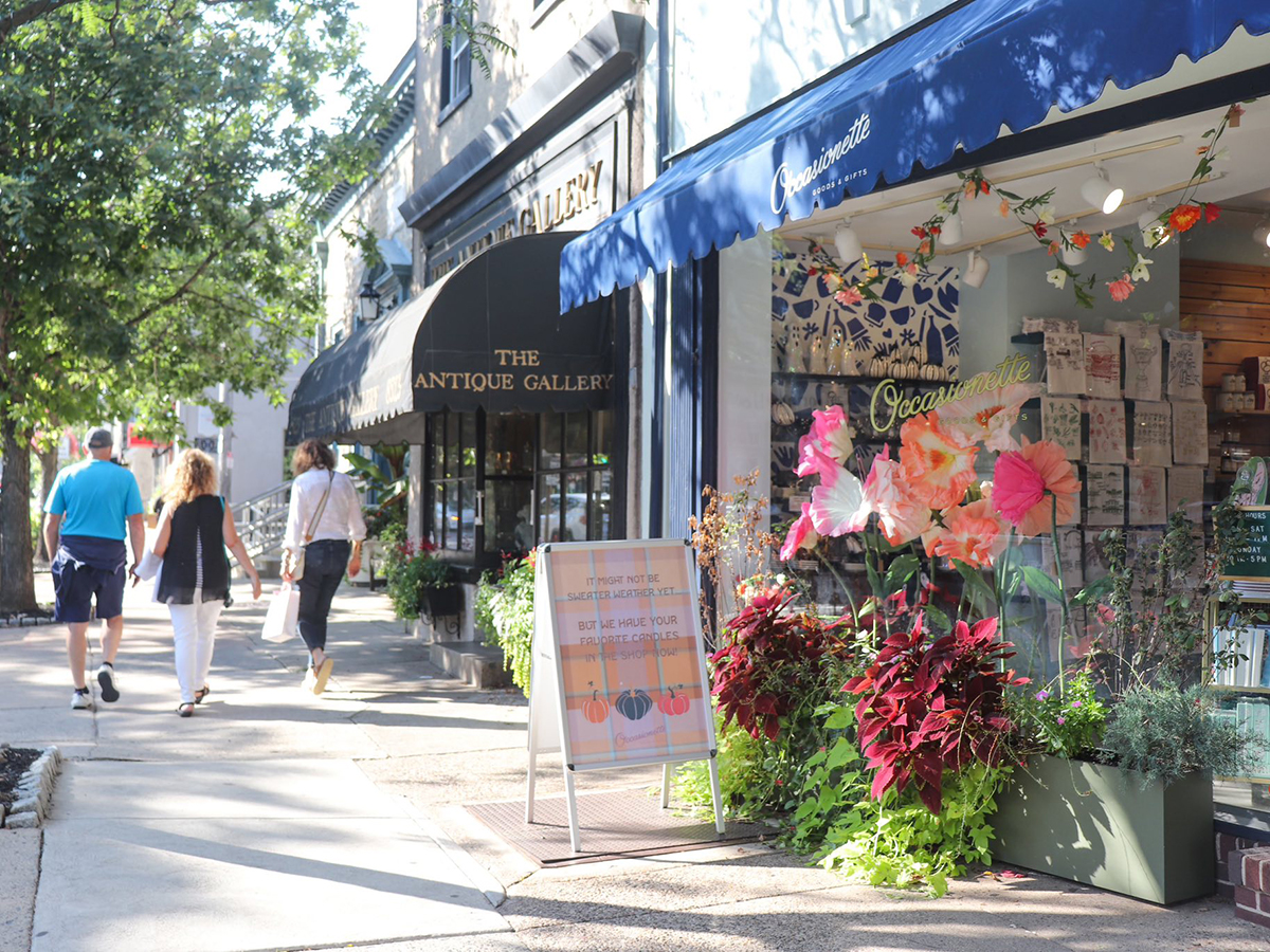 A colorful shop's window display with oversized pink and orange paper flowers outside Occasionette in Chestnut Hill.