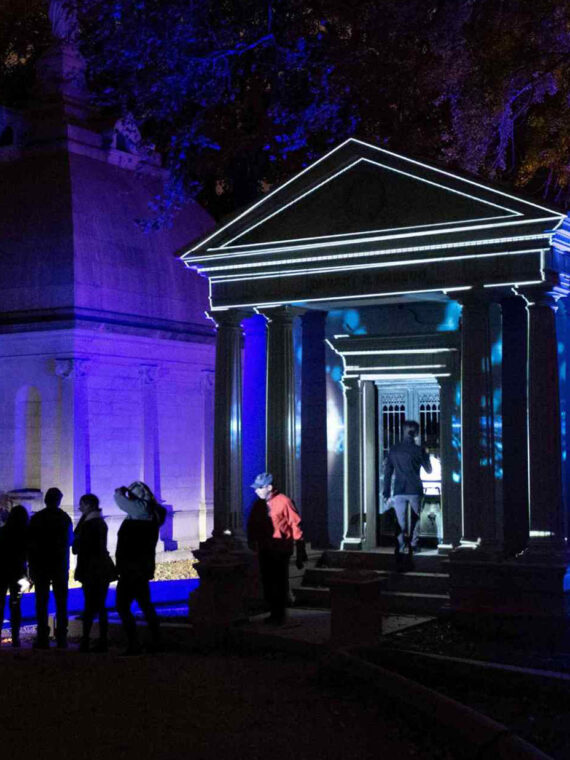 Visitors gather outside an illuminated mausoleum at Laurel Hill Cemetery during the Soul Crawl nighttime tour.