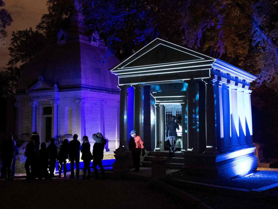 Visitors gather outside an illuminated mausoleum at Laurel Hill Cemetery during the Soul Crawl nighttime tour.