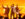 The three Jonas Brothers sing and play electric guitar on a brightly lit stage in front of a cheering crowd.