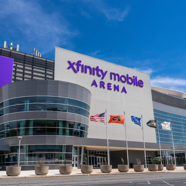 A rendering of the sleek, modern Xfinity Mobile Arena with glass walls, flags flying out front and a bright purple marquee.