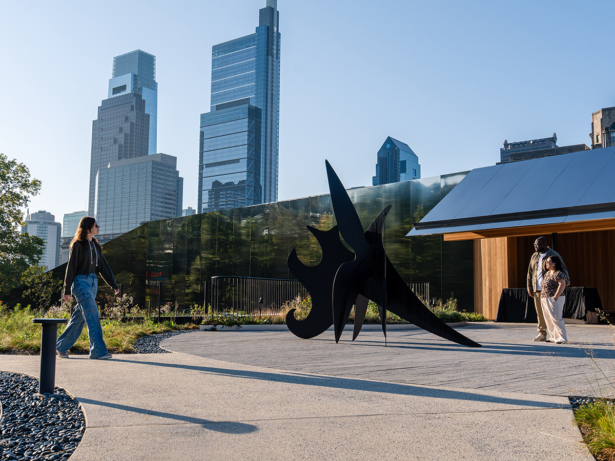 Visitors explore Calder Gardens, walking past a striking black outdoor sculpture framed by modern skyscrapers in the distance.