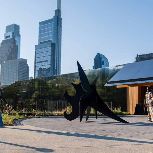 Visitors explore Calder Gardens, walking past a striking black outdoor sculpture framed by modern skyscrapers in the distance.