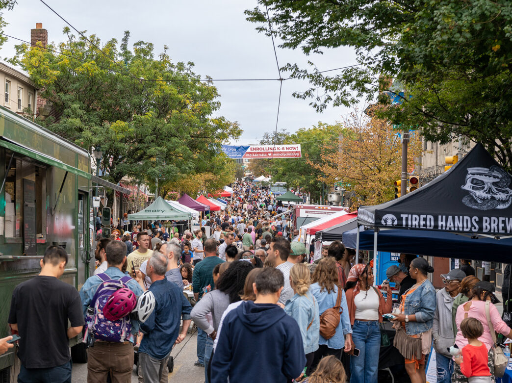A crowd of people fill a car free street lined with food vender trucks and tents during the Mt. Airy Supper Sessions.