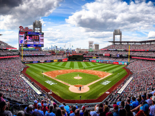 Un Citizens Bank Park bondé lors d'un match des Phillies de Philadelphie, avec des fans remplissant les gradins et l'horizon de Philadelphie au loin.
