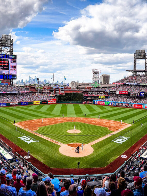 A packed Citizens Bank Park during a Philadelphia Phillies game, with fans filling the stands and the Philadelphia skyline in the distance.