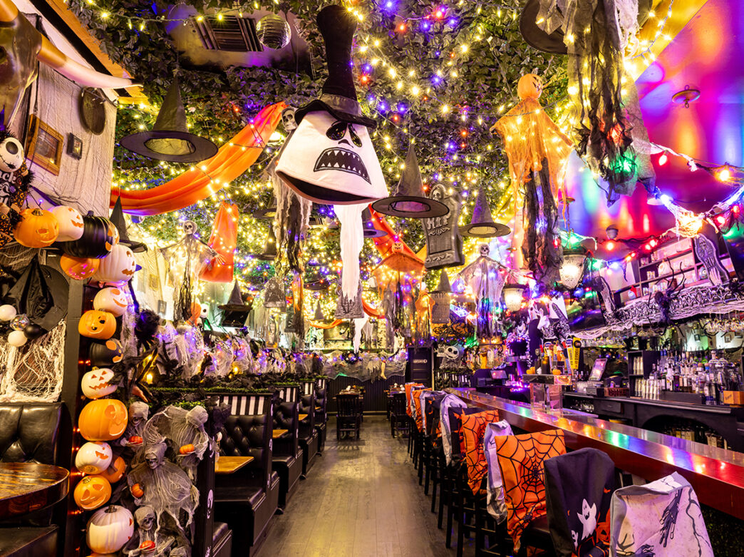 The interior of Craftsman Row Saloon decked out with glowing lights, hanging witches, pumpkins and other spooky Halloween decorations.