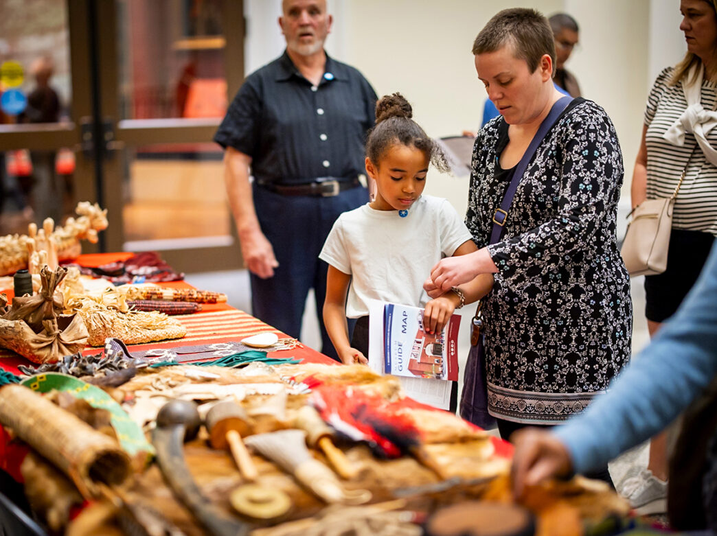 A child and adult look at a table filled with Native American artifacts and crafts during an event at the Museum of the American Revolution.