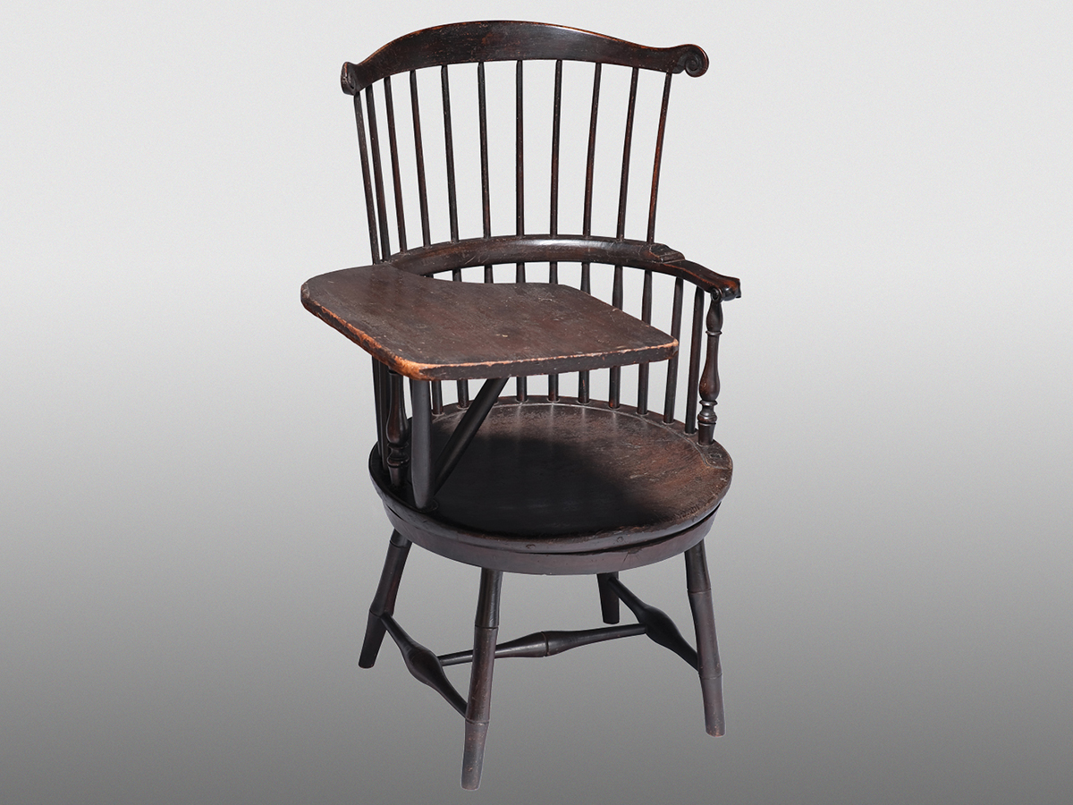 Antiguo sillón de madera de estilo Windsor con reposabrazos pivotante que servía de superficie de escritura.