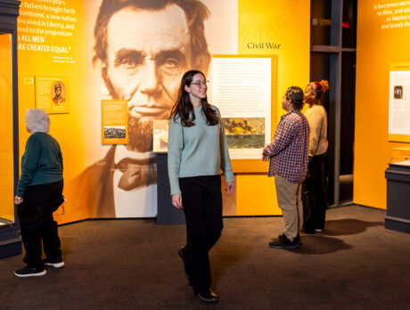 Visitors explore a new exhibit at the Museum of the American Revolution featuring artifacts, text panels and a large image of Abraham Lincoln in the gallery.