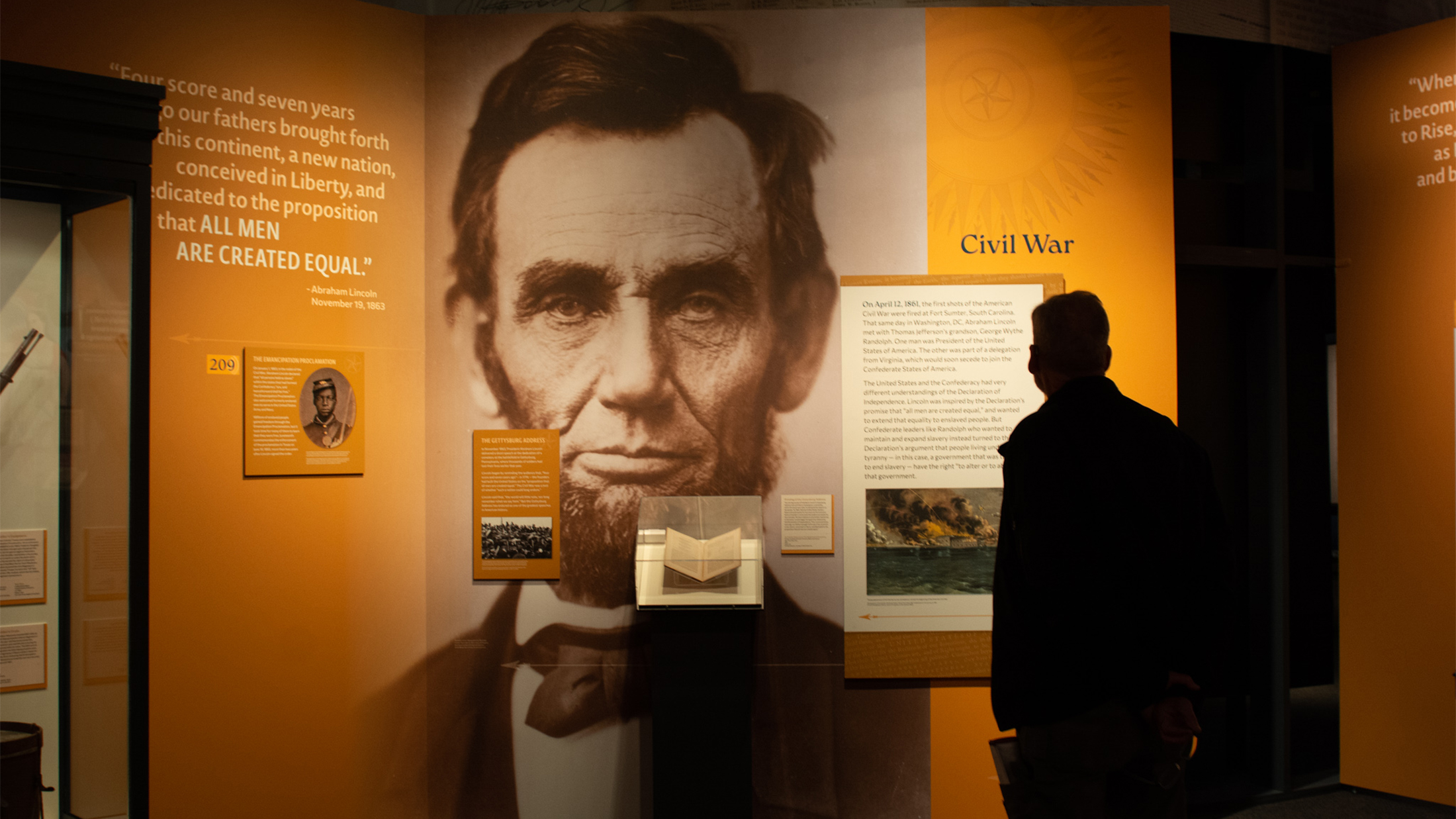 Un visitante estudia una exposición sobre Abraham Lincoln y la Guerra Civil, con un gran retrato de Lincoln y el texto del Discurso de Gettysburg.