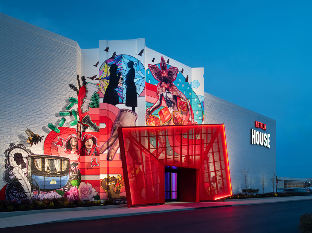 The exterior of Netflix House with a large red entrance canopy and mural showcasing Netflix characters and symbols.