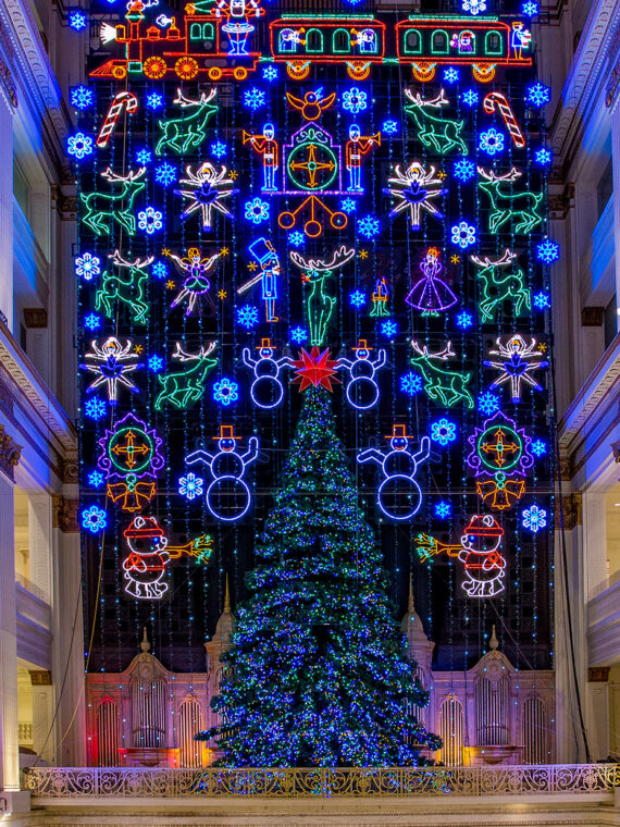 A towering Christmas tree and dazzling wall of holiday lights fill a large atrium in the Wanamaker building in Philadelphia.
