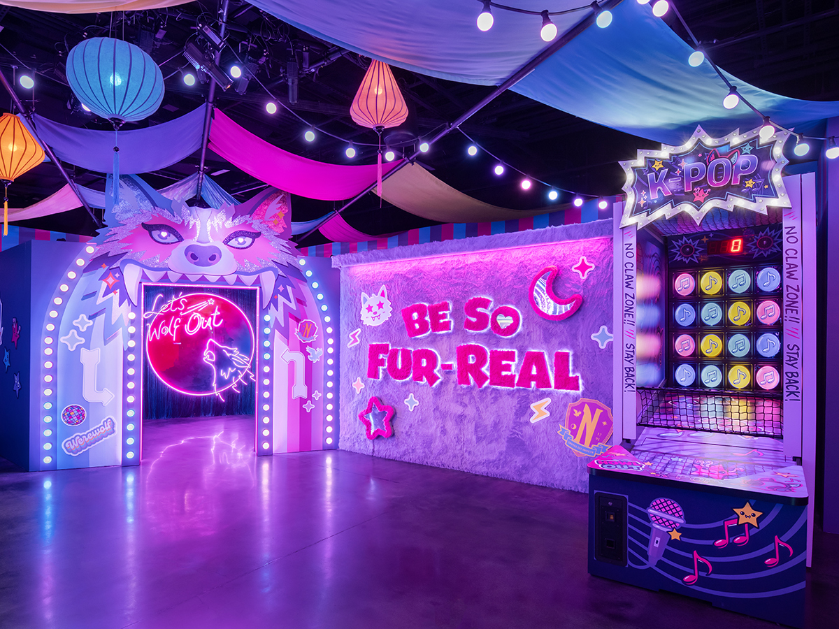 A vibrant, neon-lit room themed with werewolf imagery, including a glowing wolf-shaped doorway, colorful hanging lanterns and draped fabric.