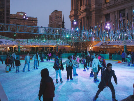 Crowds of skaters enjoy an evening on the Rothman Orthopaedics Ice Rink at Dilworth Park, with people gliding across the ice under sparkling silver decorations.