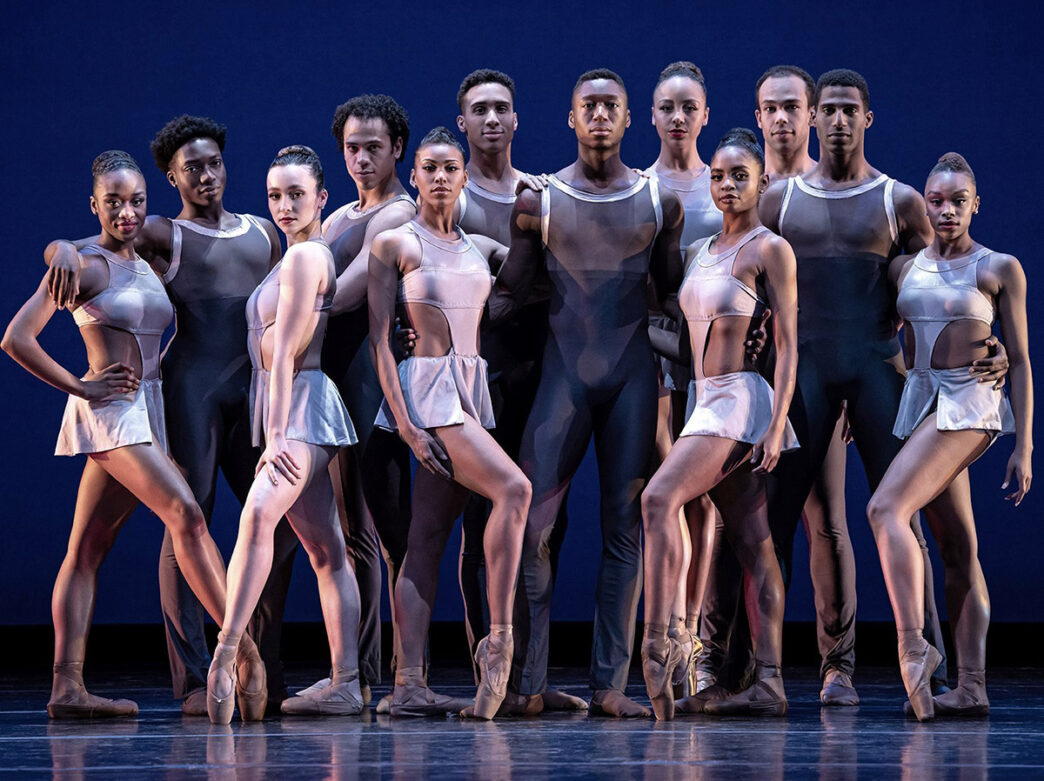 Les hommes, vêtus de justaucorps noirs, et les femmes, vêtues de justaucorps et de jupes argentés, du Dance Theatre of Harlem posent devant l'appareil photo.