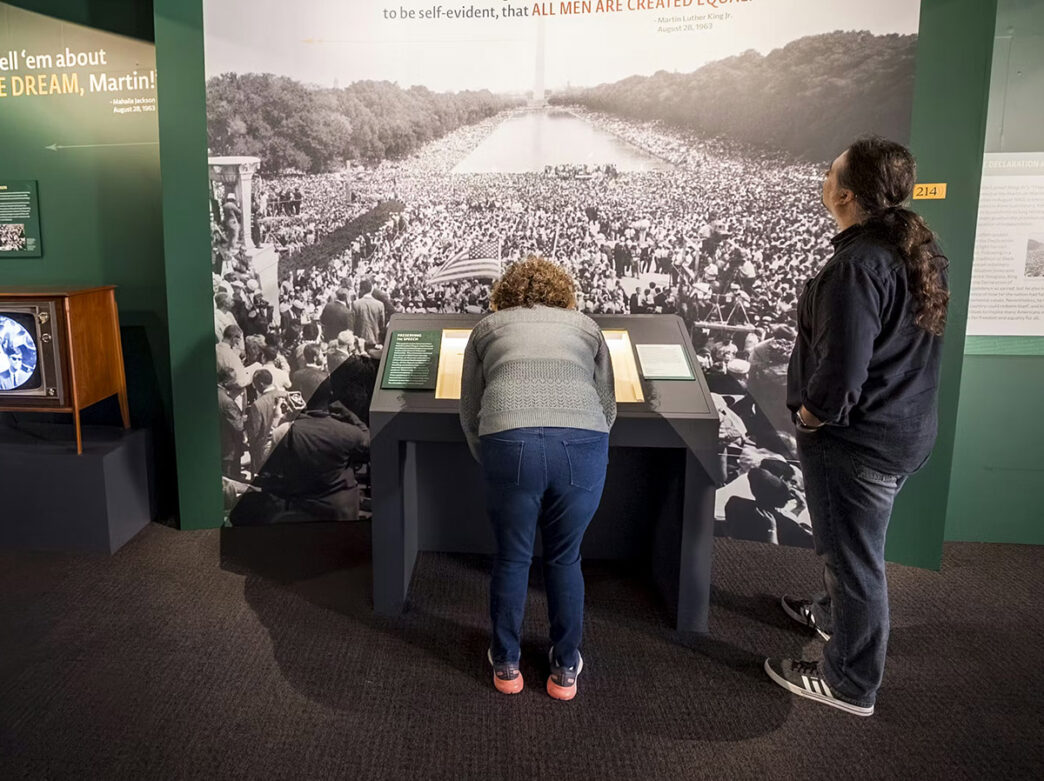 Deux visiteurs explorent une exposition présentant une grande image de la foule lors de la Marche sur Washington de 1963.
