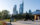 People walk by an outdoor sculpture with the Philadelphia skyline in the background on a sunny day.