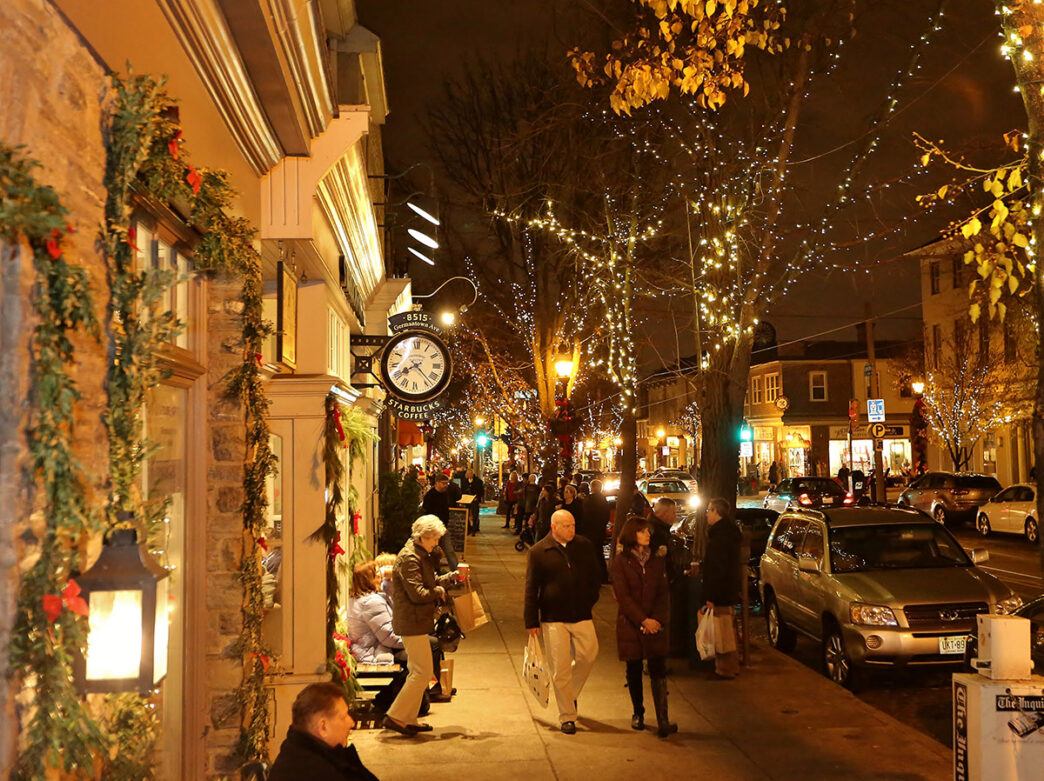 People walk down the street at night on Germantown Avenue in Chestnut HIll during the holiday season