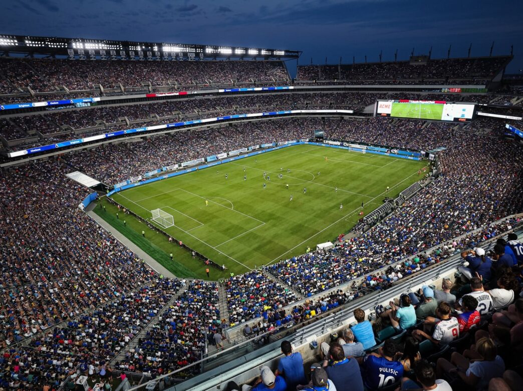 Group of fans watching soccer players at night at Lincoln Financial Field