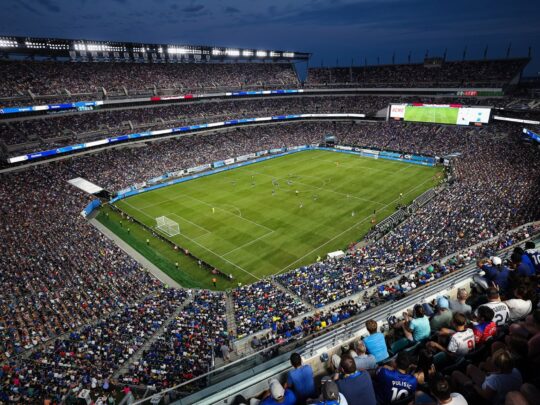 Group of fans watching soccer players at night at Lincoln Financial Field