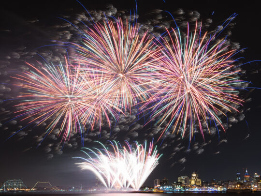 Colorful fireworks explode in the night sky above the Delaware River in Philadelphia.