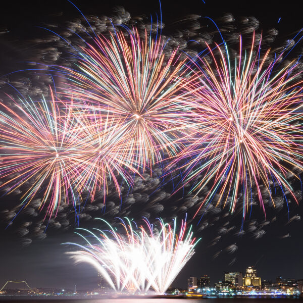 Colorful fireworks explode in the night sky above the Delaware River in Philadelphia.