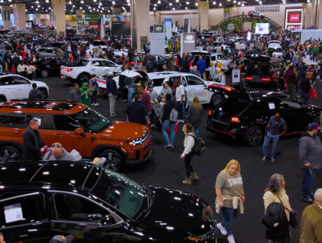 People walk through a busy convention center filled with new cars and SUVS at the Philadelphia Auto Show.