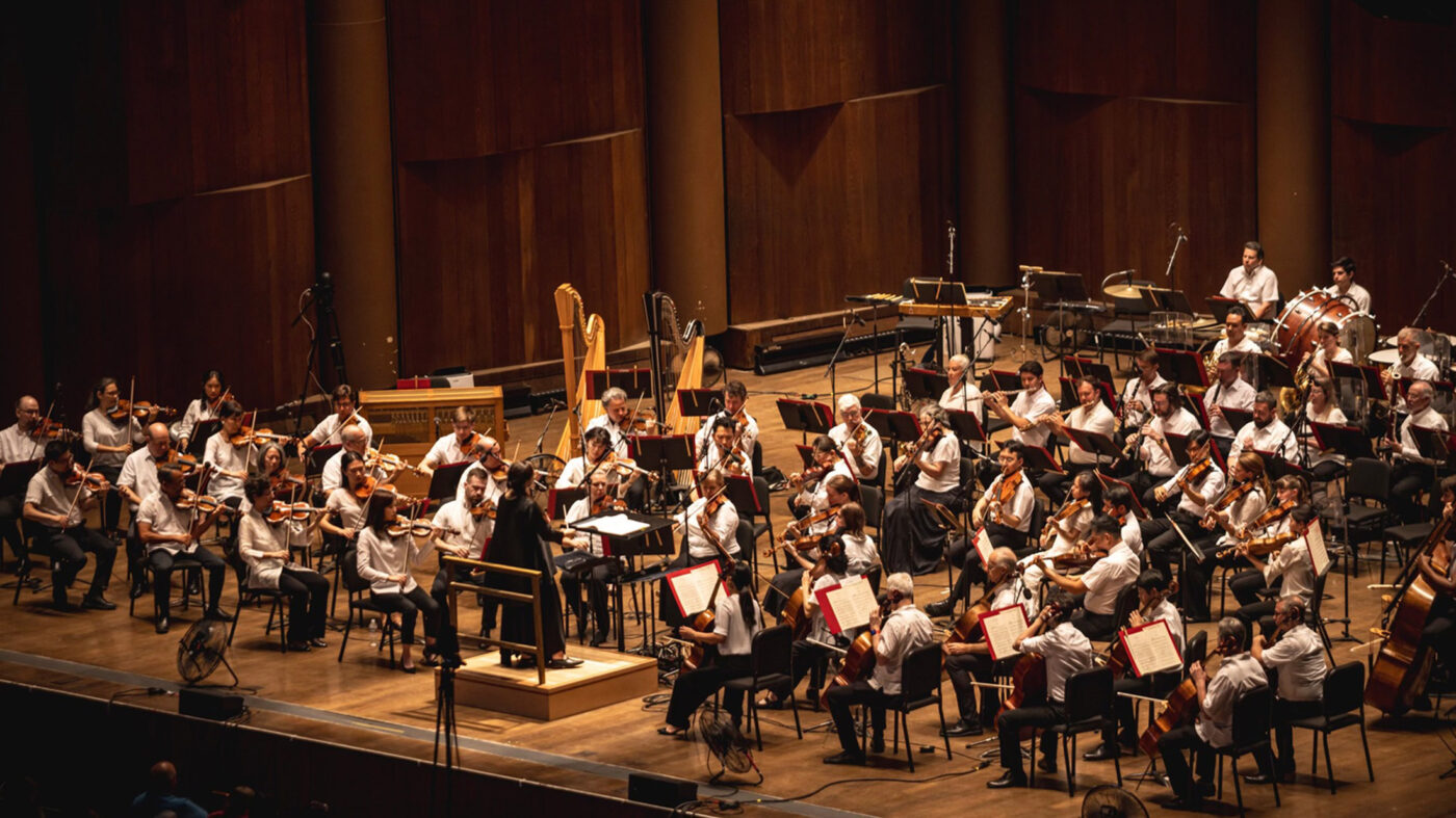 A wide shot of Philadelphia Orchestra performers playing a variety of classical instruments on a wooden stage