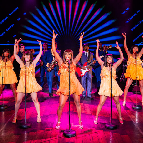 Vrouwen gekleed in geel dansen op een roze podium voor een uitvoering van de musical Tina Turner