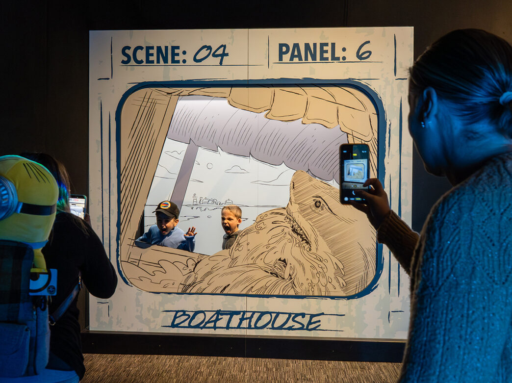 Dos niños posan junto a una muestra del guion gráfico de la película «Tiburón» en la exposición «Parques temáticos de Universal» del Instituto Franklin.