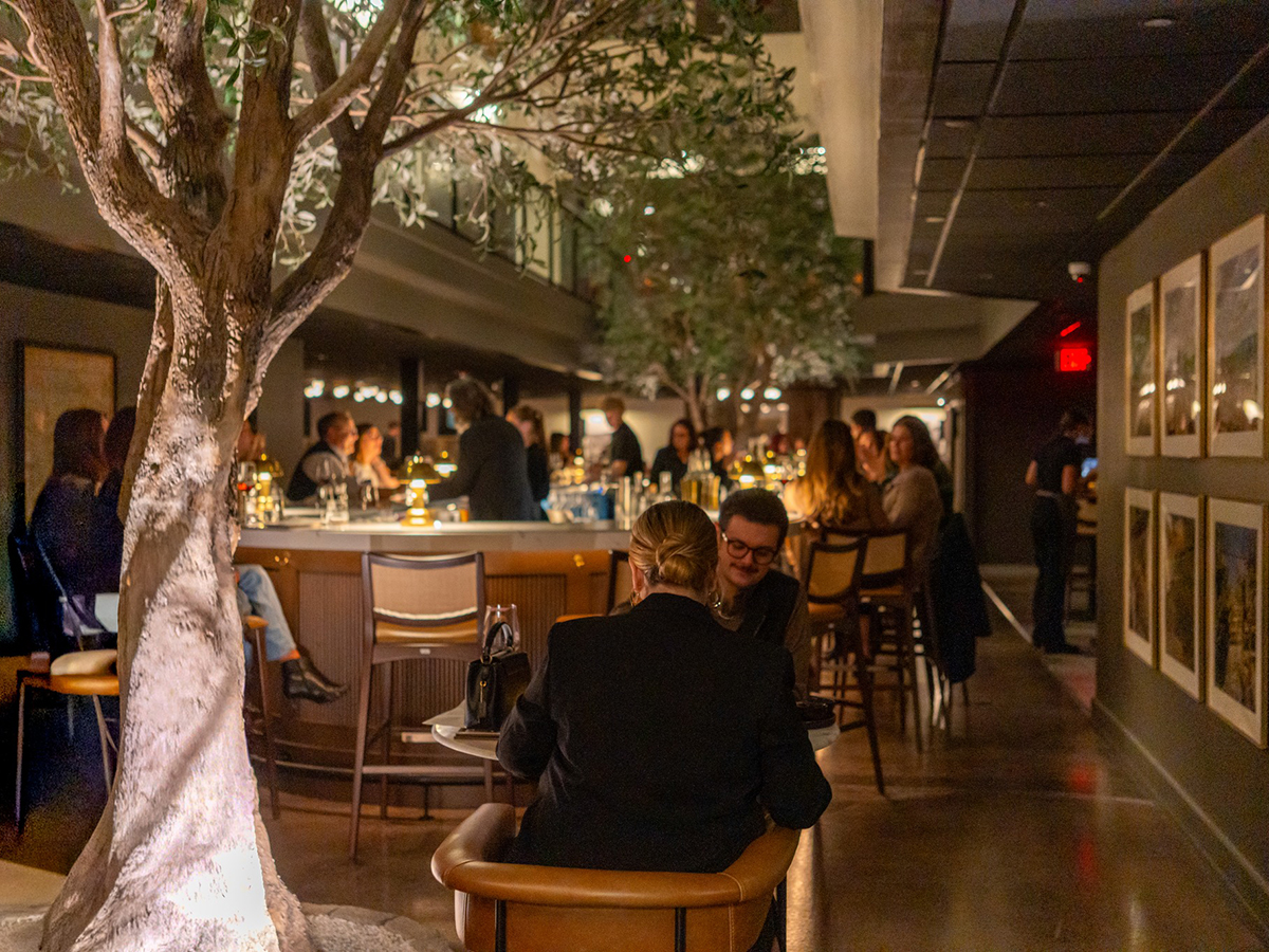 Chez Turks Head Wines, les clients prennent place au bar, baigné d'une lumière chaleureuse et situé sous un sapin d'intérieur, ce qui crée une ambiance conviviale pour le dîner.