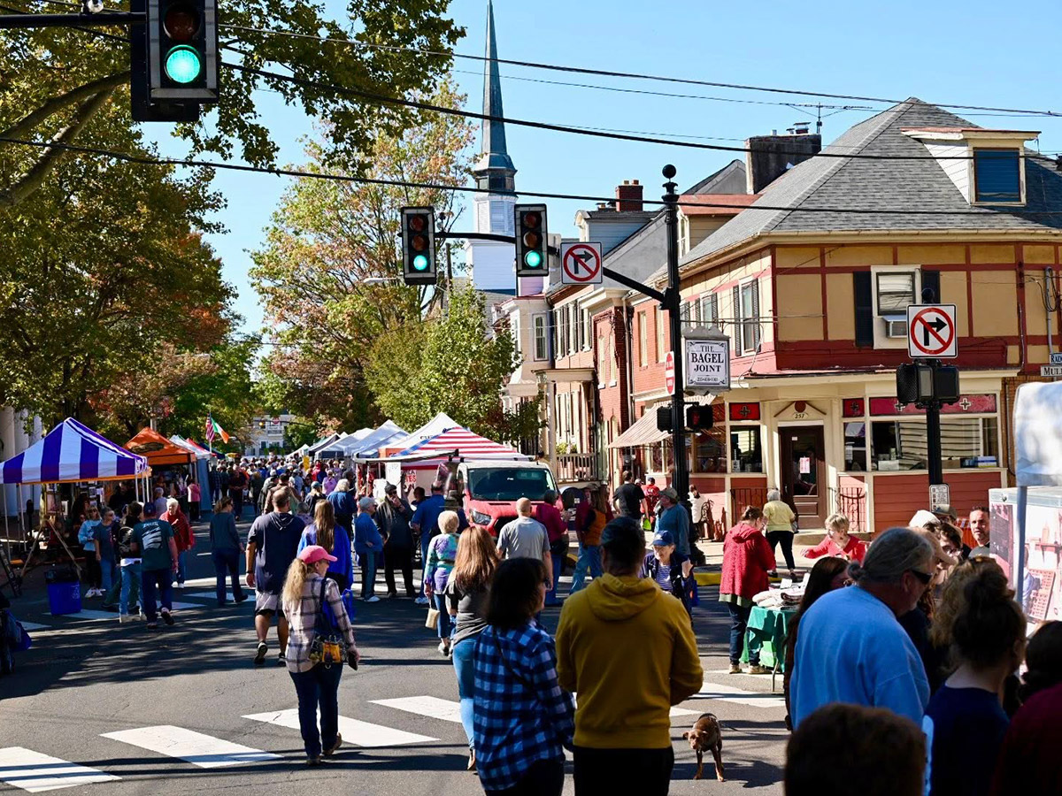 A crowd of people explores the tents and stalls of a lively street festival.