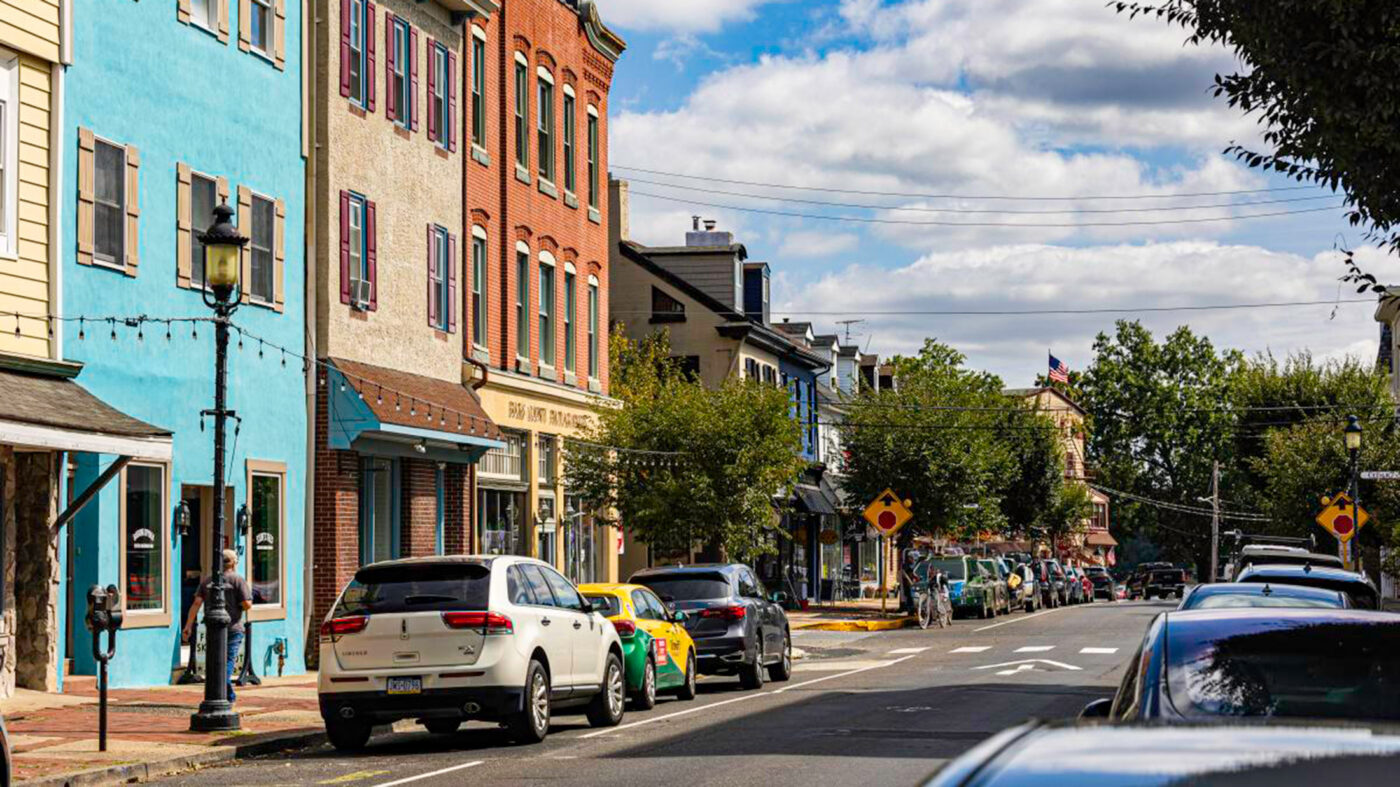 Colorful storefronts and parked cars along a main street in Bristol, PA.