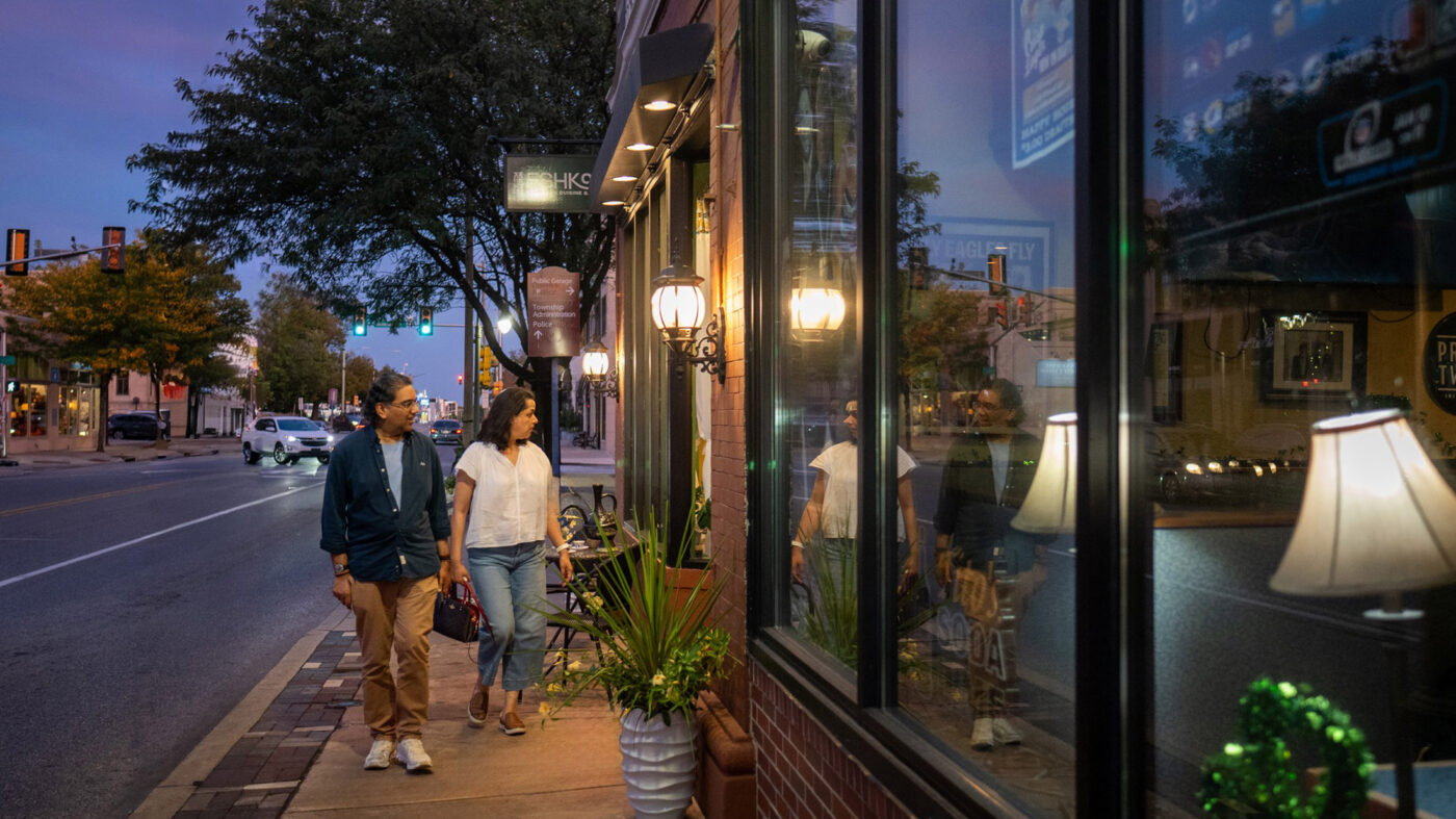 A casually dressed couple window shops while walking past Lancaster Avenue storefronts.
