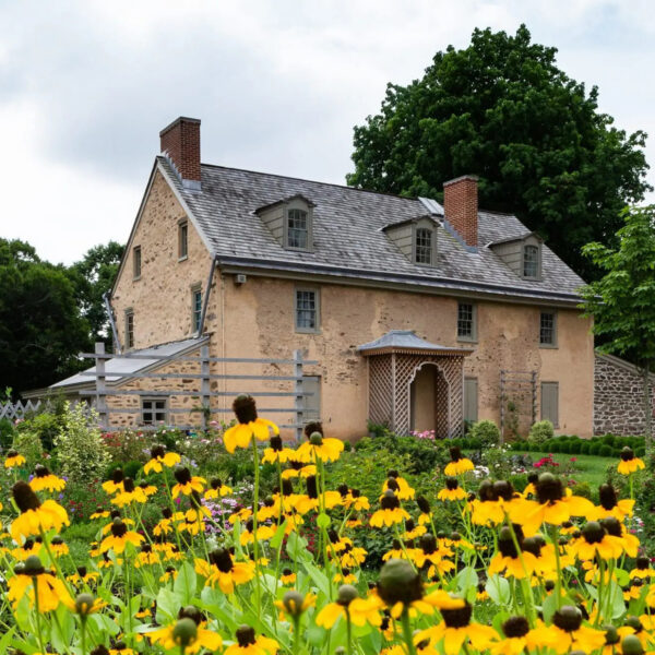 Exterieur van Bartram's Garden Historic House met bloemen, waaronder Black Eyed Susans, op de voorgrond.