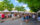 A large crowd of people congregate in front of a row white vendor tents.