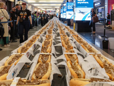 Dozens of cheesesteaks are lined up on a black table inside Philadelphia International Airport.