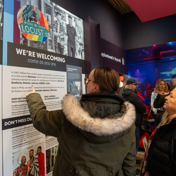 A visitor points at a display panel inside of the Philly Pride Visitor Center.