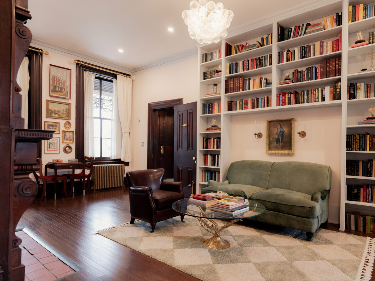 A room with a leather chair, green couch, glass coffee table, and bookshelves at the Bookhouse at Faunbrook.