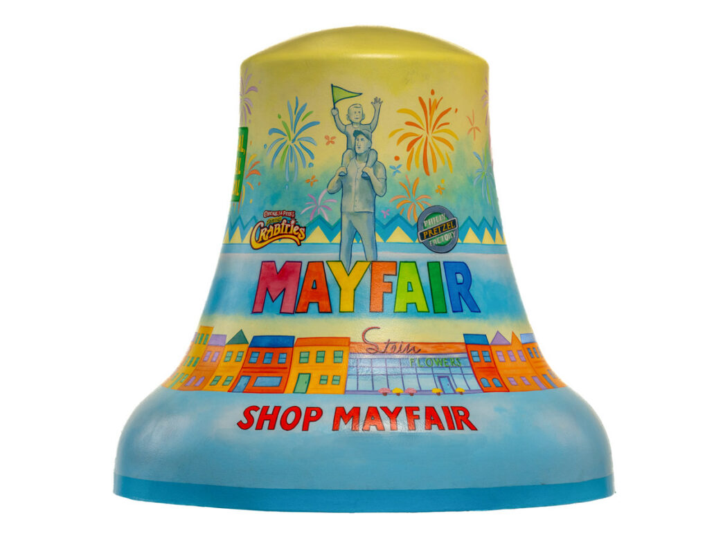 Colorfully painted bell representing Mayfair for Philadelphia250’s Bells Across PA, featuring fireworks, neighborhood storefronts, and the words “Mayfair” and “Shop Mayfair” in bright lettering.