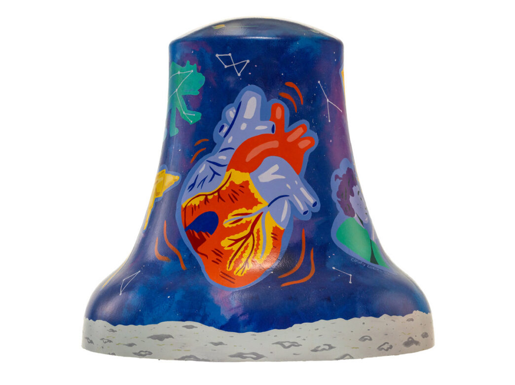 Bell sculpture titled “Connection Between the Stars” from Philadelphia250’s Bells Across PA, featuring a vibrant anatomical heart at the center set against a deep blue, star-filled sky. Constellations and abstract shapes surround the heart, with cosmic imagery and small celestial elements scattered across the surface, suggesting a connection between humanity and the universe.