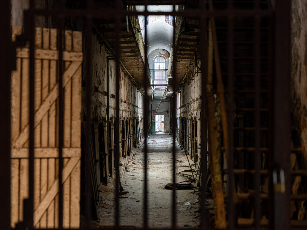 A view through the bars of a long, eerie alleyway at Eastern State Penitentiary.