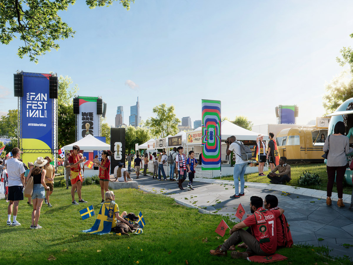 Los aficionados se relajan y se reúnen en un prado durante el Festival de Aficionados de la Copa Mundial de la FIFA 2026 en Filadelfia, mientras exploran los puestos de comida y las casetas de los vendedores, con el perfil urbano de la ciudad y los coloridos carteles del festival como telón de fondo.